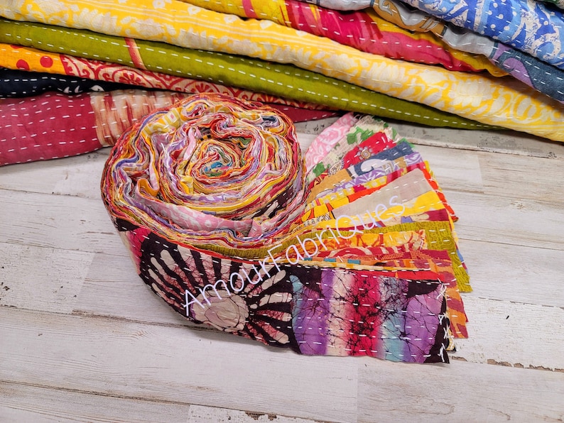 May include: A roll of colorful fabric scraps, tied together with a white string. The fabric is a mix of patterns and colors, including pink, yellow, blue, and green. The fabric is labeled "Amour Fabriques".