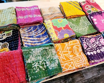 Könnte beinhalten: Eine Sammlung bunter Stoffquadrate mit verschiedenen Mustern, darunter florale, geometrische und Paisley-Designs. Die Quadrate sind übereinander gestapelt und bilden so eine optisch ansprechende Darstellung.