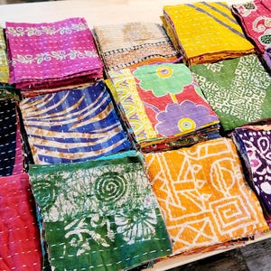 May include: A collection of colorful fabric squares with various patterns, including floral, geometric, and paisley designs. The squares are stacked and arranged in a grid pattern, creating a visually appealing and textured display.