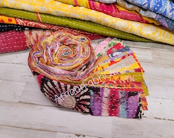 May include: A roll of colourful fabric scraps, tied together with a white string. The fabric is a mix of patterns and colours, including pink, yellow, blue, and green. The fabric is labelled "Amour Fabriques".