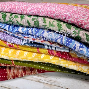 May include: A stack of colorful kantha quilts with floral patterns. The quilts are made of cotton and are hand-stitched. They are perfect for adding a touch of bohemian style to your home.