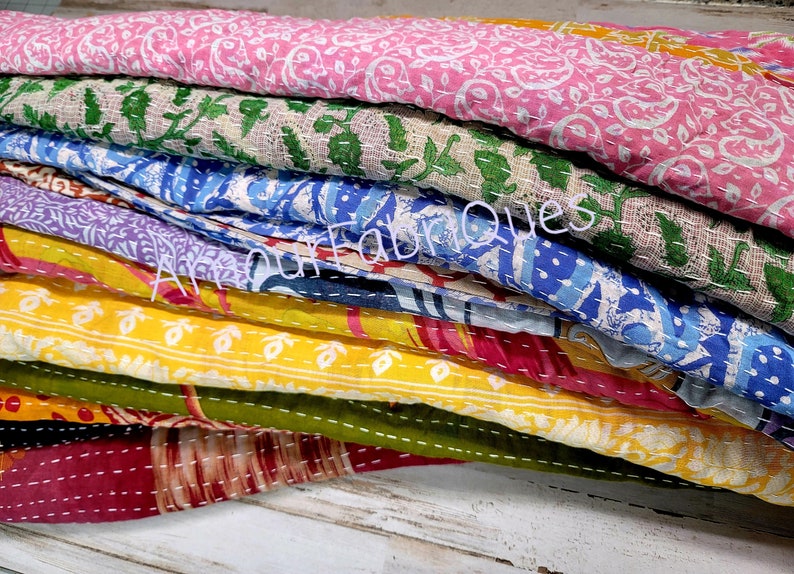 May include: A stack of colorful kantha quilts with floral patterns. The quilts are made of cotton and are hand-stitched. They are perfect for adding a touch of bohemian style to your home.