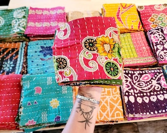 May include: A stack of colorful fabric squares with various patterns and designs. The fabric squares are quilted and have a vintage look.