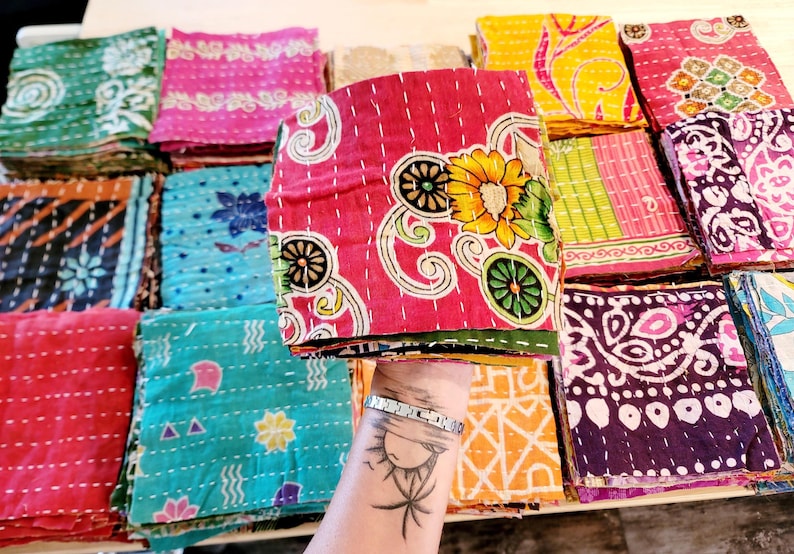 May include: A stack of colorful fabric squares with various patterns and designs. The fabric squares are quilted and have a vintage look.