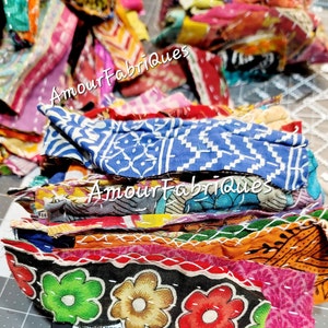 May include: A stack of colorful fabric scraps with a variety of patterns and textures. The fabric scraps are sewn together with white thread. The text "Amour Fabriques" is visible on the fabric scraps.