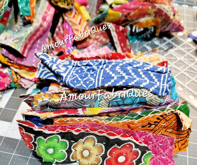 May include: A stack of colorful fabric scraps with a variety of patterns and textures. The fabric scraps are sewn together with white thread. The text "Amour Fabriques" is visible on the fabric scraps.