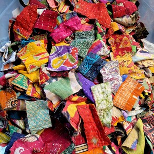 May include: A pile of colorful fabric scraps, perfect for quilting or other craft projects. The scraps are made of various fabrics, including cotton, silk, and linen. They are all different sizes and shapes, and some have been stitched together.