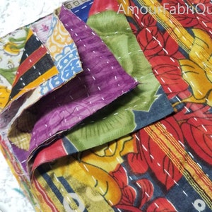 May include: A stack of colorful fabric squares with floral patterns, stitched together with white thread. The fabric is a mix of red, yellow, green, blue, and purple.