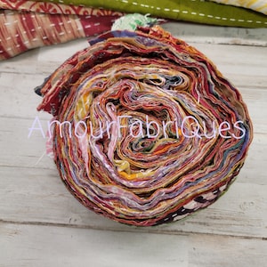 May include: A roll of colorful fabric scraps, tightly wound and ready for crafting projects. The fabric is a mix of red, orange, yellow, green, blue, and purple, with a variety of patterns and textures. The roll is about 10 inches in diameter.