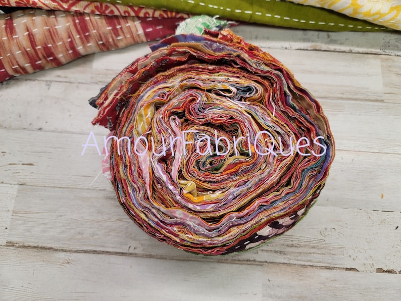 May include: A roll of colorful fabric scraps, tightly wound and ready for crafting projects. The fabric is a mix of red, orange, yellow, green, blue, and purple, with a variety of patterns and textures. The roll is about 10 inches in diameter.
