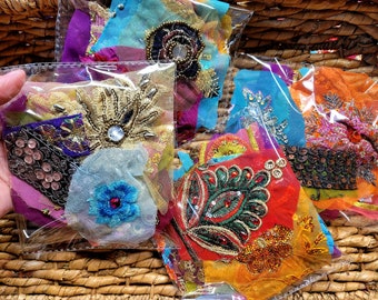 May include: Assortment of colorful fabric scraps with intricate embroidery and sequins, packaged in clear plastic bags. The fabric scraps feature various designs, including floral motifs, paisley patterns, and geometric shapes. The sequins and beads add sparkle and texture to the fabric.