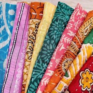 May include: A stack of colorful fabric squares with various patterns, including floral, geometric, and paisley designs. The fabric is soft and has a vintage look.