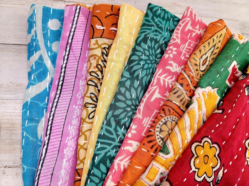 May include: A stack of colorful fabric squares with various patterns, including floral, geometric, and paisley designs. The fabric is soft and has a vintage look.