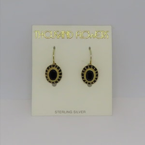 May include: A pair of sterling silver earrings with black oval stones set in gold-toned frames. The earrings are on a white card with the text "THOUSAND FLOWERS" and "STERLING SILVER".