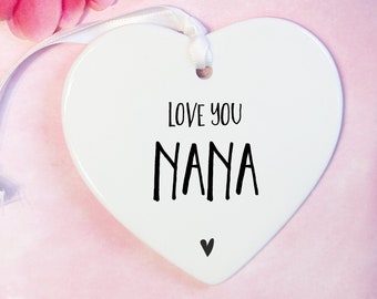 May include: White ceramic heart-shaped ornament with a black ribbon and the text "Love you Nana" in black script.
