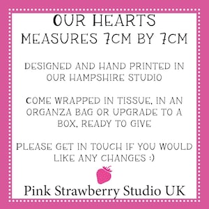 May include: A white square sign with a pink border and white dots, featuring black text: OUR HEARTS MEASURES 7CM BY 7CM, DESIGNED AND HAND PRINTED IN OUR HAMPSHIRE STUDIO, COME WRAPPED IN TISSUE, IN AN ORGANZA BAG OR UPGRADE TO A BOX, READY TO GIVE, PLEASE GET IN TOUCH IF YOU WOULD LIKE ANY CHANGES :), a small pink strawberry icon, and Pink Strawberry Studio UK.