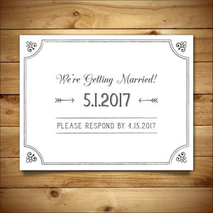 May include: A white wedding announcement card with a black border and ornate corners. The text reads "We're Getting Married! 5.1.2017 Please Respond by 4.15.2017"