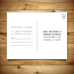 May include: A white RSVP postcard with black text. The text reads "We have reserved seats for you. Accepts with pleasure. Declines with regret."  The postcard also includes the names "Emily Matthews & Andrew Reynolds" and their address "789 Matrimony Lane, Paradise, CA 90000".