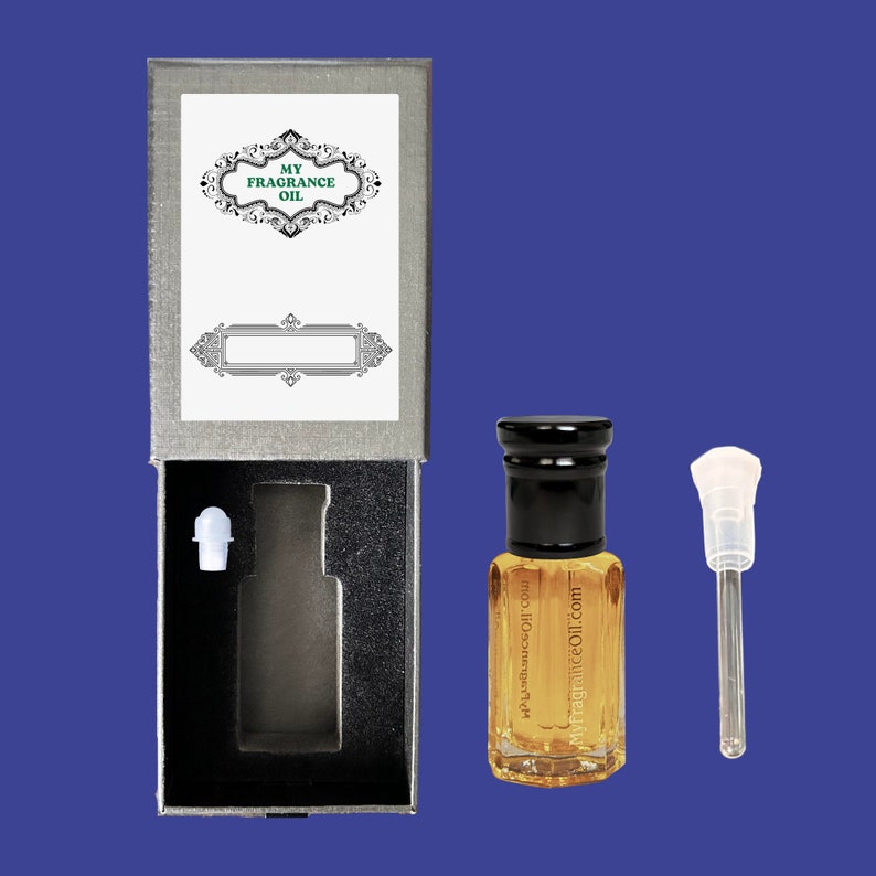 K&ouml;nnte beinhalten: Eine silberne Box mit einem Etikett mit der Aufschrift "My Fragrance Oil" und eine kleine Glasflasche mit schwarzem Verschluss und einem klaren Tropfer. Die Flasche ist mit einer goldenen Fl&uuml;ssigkeit gef&uuml;llt. Die Flasche steht auf einer blauen Oberfl&auml;che.