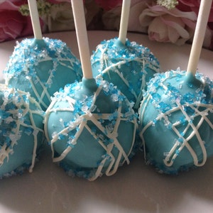 May include: Blue cake pops decorated with white icing and blue sprinkles on sticks.