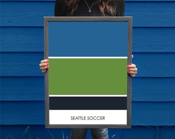 May include: A framed print with a color block design in shades of blue, green, and black. The print has the text "SEATTLE SOCCER" at the bottom.