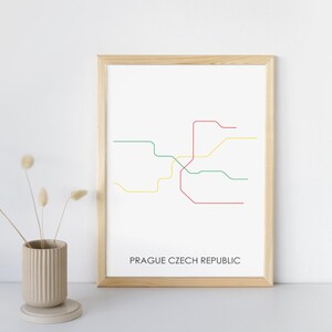 May include: A framed print of the Prague subway map with lines in red, green, and yellow. The text "Prague Czech Republic" is at the bottom of the print.