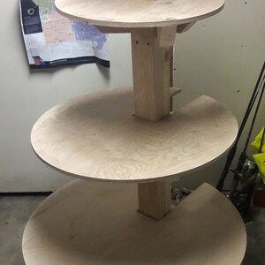 Puede incluir: Un soporte de madera de varios niveles con cuatro estantes circulares. El soporte est&aacute; hecho de madera natural y tiene un aspecto r&uacute;stico.