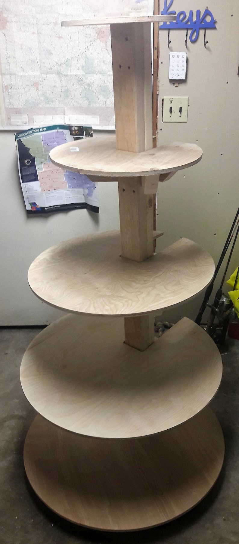 Puede incluir: Un soporte de madera de varios niveles con cuatro estantes circulares. El soporte est&aacute; hecho de madera natural y tiene un aspecto r&uacute;stico.