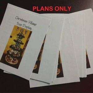Puede incluir: Una pila de papeles blancos con el texto "Christmas Village Tree Display" y la palabra "JOY" en letras doradas en el papel superior. El texto "PLANS ONLY" est&aacute; escrito en letras rojas en la parte superior de la pila.
