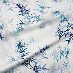 May include: White fabric featuring a repeating pattern of blue bamboo branches and leaves. The design uses varying shades of blue, creating a watercolour effect. The fabric has a soft, flowing appearance, suggesting it is lightweight and suitable for clothing or home decor.