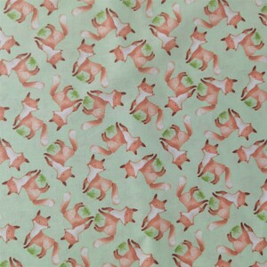 May include: A green fabric with a repeating pattern of orange foxes. The foxes are facing different directions and are in various poses.