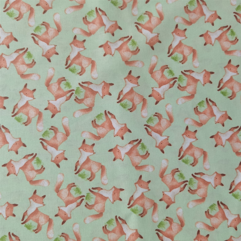 May include: A green fabric with a repeating pattern of orange foxes. The foxes are facing different directions and are in various poses.
