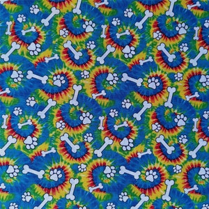 Pu&ograve; includere: Un tessuto tie-dye blu, giallo, rosso e verde con un motivo ripetuto di impronte di zampe bianche e forme di ossa.