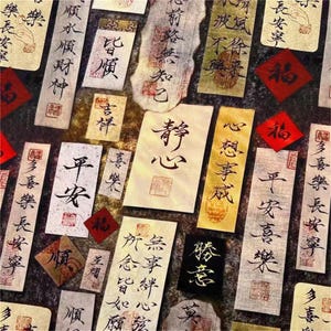 May include: An assortment of rectangular and square paper pieces with Chinese calligraphy in black ink. The papers vary in color, including white, beige, and gold, and are arranged on a dark background. Red square stamps and calligraphy are also present.