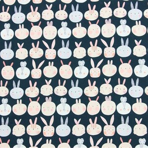 Peut inclure: Un tissu bleu fonc&eacute; avec un motif r&eacute;p&eacute;t&eacute; de visages de lapins blancs, roses et bleu clair. Les lapins ont des oreilles et des nez roses, et certains ont de petits c&oelig;urs ou des n&oelig;uds sur la t&ecirc;te.