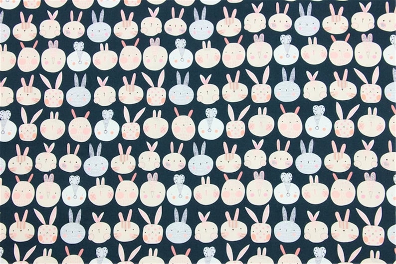 Peut inclure: Un tissu bleu fonc&eacute; avec un motif r&eacute;p&eacute;t&eacute; de visages de lapins blancs, roses et bleu clair. Les lapins ont des oreilles et des nez roses, et certains ont de petits c&oelig;urs ou des n&oelig;uds sur la t&ecirc;te.