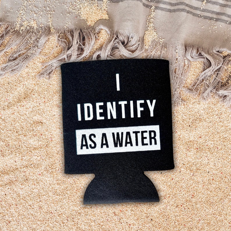 Op de afbeelding: Zwarte neopreen koelbox voor blikjes met witte tekst die "Ik identificeer me als water" luidt.