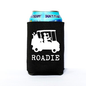 May include: Black neoprene can cooler with a white silhouette of a golf buggy and the word "ROADIE" printed on it.