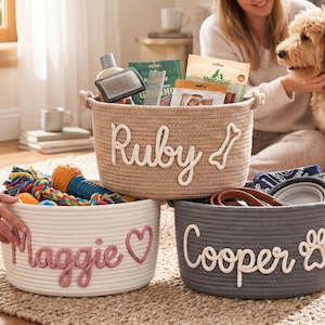 May include: Three woven rope baskets for pets, each with a name. The beige basket says "Ruby" with a bone, the white basket says "Maggie" with a heart, and the gray basket says "Cooper" with a paw print.