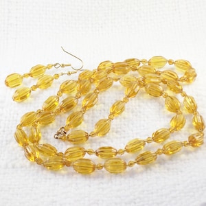 May include: A set of amber glass bead earrings and a matching necklace. The beads are oval shaped and have a ribbed texture.