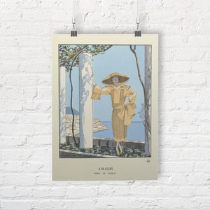 May include: A vintage illustration of a woman wearing a yellow dress and a large straw hat. She is standing in a garden setting with a view of the ocean in the background. The text "AMALFI" and "ROBE DE WORTH" is printed below the image.