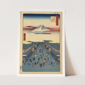 May include: A woodblock print depicting a bustling street scene in Edo, Japan, with Mount Fuji in the background. The print is in shades of blue, green, and red, with a white mountain peak. The street is lined with shops and stalls, and people are walking and shopping.