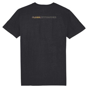 Op de afbeelding: Donkergrijs t-shirt met de gouden tekst "@LOOKSKYWANDER" op de rug. De tekst bevat een kompasontwerp. Het t-shirt is gemaakt van een zacht materiaal.
