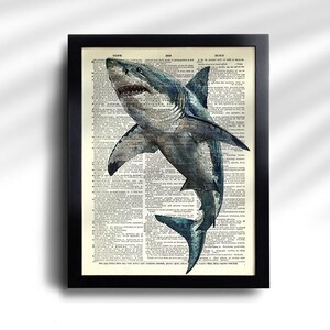 May include: Framed print featuring a detailed illustration of a great white shark. The shark is depicted in shades of gray and blue, set against a backdrop of vintage dictionary pages. The black frame adds a classic touch to the artwork.