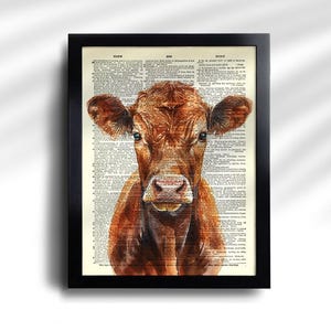 May include: A framed print featuring a watercolor painting of a brown cow. The cow is centered, with a detailed depiction of its face and fur. The background is a vintage dictionary page, adding a rustic touch to the artwork.