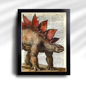 Puede incluir: Impresi&oacute;n enmarcada con una ilustraci&oacute;n detallada de un dinosaurio Estegosaurio. La obra de arte est&aacute; ambientada sobre un fondo de p&aacute;gina de diccionario antiguo, con el dinosaurio representado en tonos marrones, naranjas y rojos. El marco es negro.