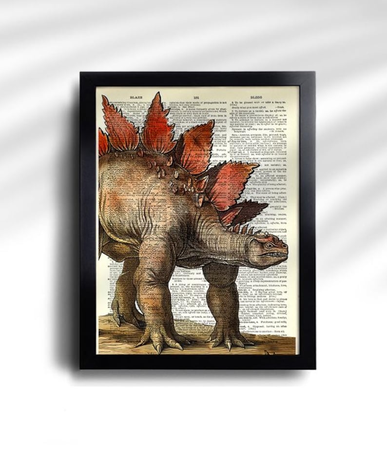 Puede incluir: Impresi&oacute;n enmarcada con una ilustraci&oacute;n detallada de un dinosaurio Estegosaurio. La obra de arte est&aacute; ambientada sobre un fondo de p&aacute;gina de diccionario antiguo, con el dinosaurio representado en tonos marrones, naranjas y rojos. El marco es negro.