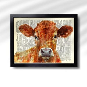 May include: A framed watercolor print of a cow's head. The cow is a reddish-brown color, with large ears and a gentle expression. The background is a vintage dictionary page, and the frame is black.