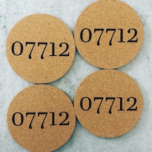 May include: Four round cork coasters with the number "07712" printed in black. The coasters are a light brown color and have a textured surface. The coasters are arranged in a square.