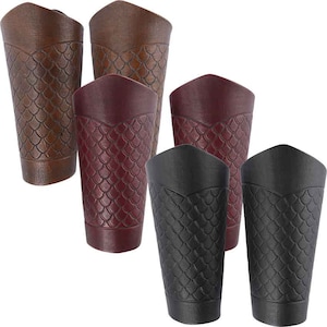 May include: Set of five leather arm guards in brown, burgundy, and black. Each guard has a scale-like pattern.